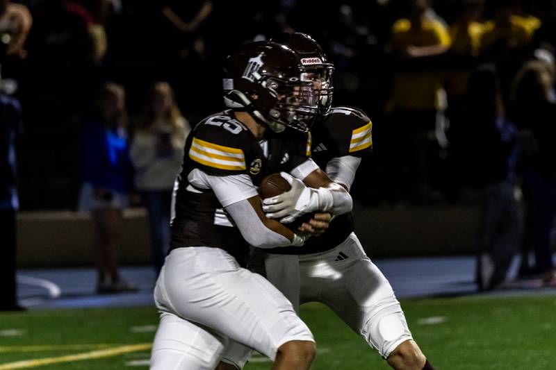 Joliet Catholic's Lucas Simulick hands-off the ball to Anthony Finnegan during a varsity football game against Lyons Township at Busey Bank Field at Joliet Memorial Stadium on Aug. 29, 2025.