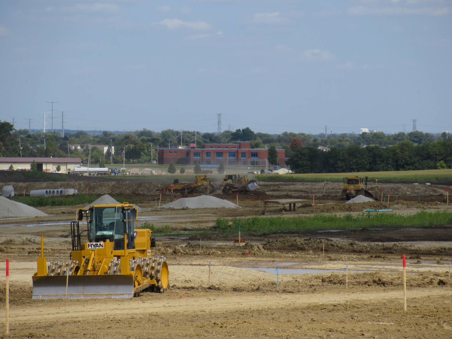 Oswego East High school can be seen from the construction at the southeast corner of Wolf’s Crossing Harvey roads, where Emblem's 13 3-story apartment buildings will be developed by Lennar. Photo taken Sept. 15 2022.
