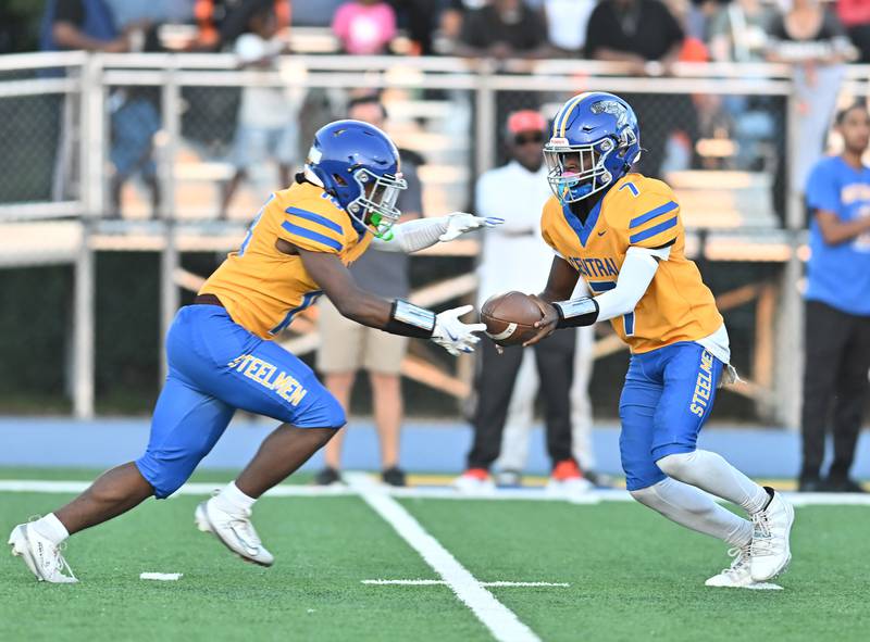 Joliet Central's Jeffrey Woods (7) hands the ball off to Tristen Sellers during the conference game against Plainfield East's on Friday, SEP. 12, 2025, at Joliet.