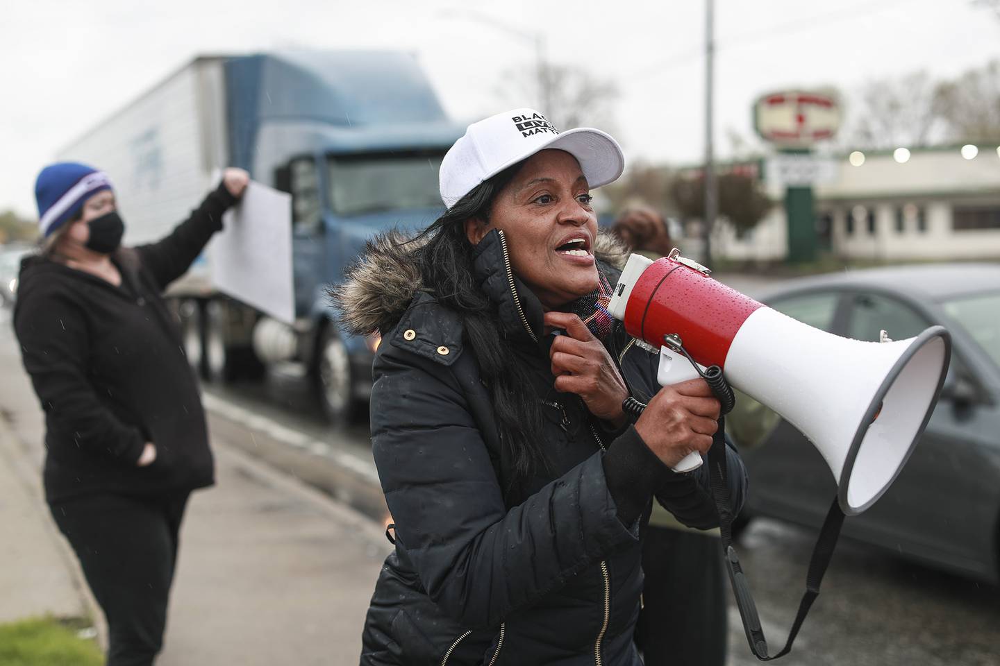 Local activist and community member Trista Graves Brown calls speaks through a megaphone to motorists on Monday, April 19, 2021, at the intersection of Jefferson St. and Larkin Ave. in Joliet, Ill. Members of Joliet's community of faith came together to raise awareness and call for justice for George Floyd.