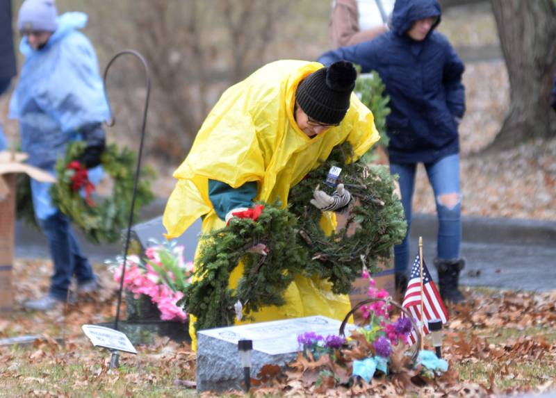 Debbie Oracki of Forreston places a wreath at a veteran's grave during the Wreaths Across America event at Daysville Cemetery. east of Oregon, on Saturday, Dec. 16, 2023. Oracki's son is a Navy veteran and her daughter is currently serving in the Navy. "There is a certain pride you feel today by doing this," she said.