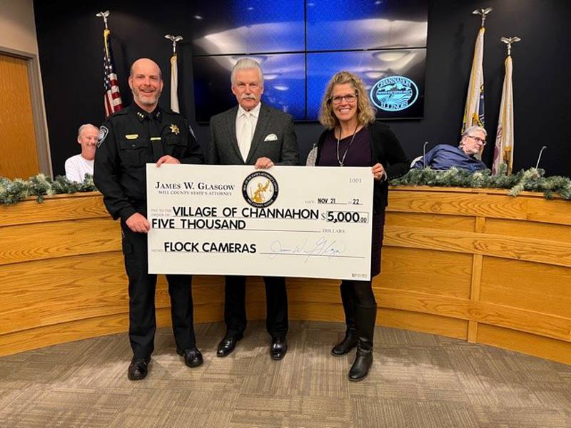 Channahon Police Chief Shane Casey (left), Will County State’s Attorney James Glasgow and Village President Missey Schumacher holding a $5,000 check for the payment of Flock Safety cameras at a Channahon village board meeting on Monday, Nov. 21, 2022.