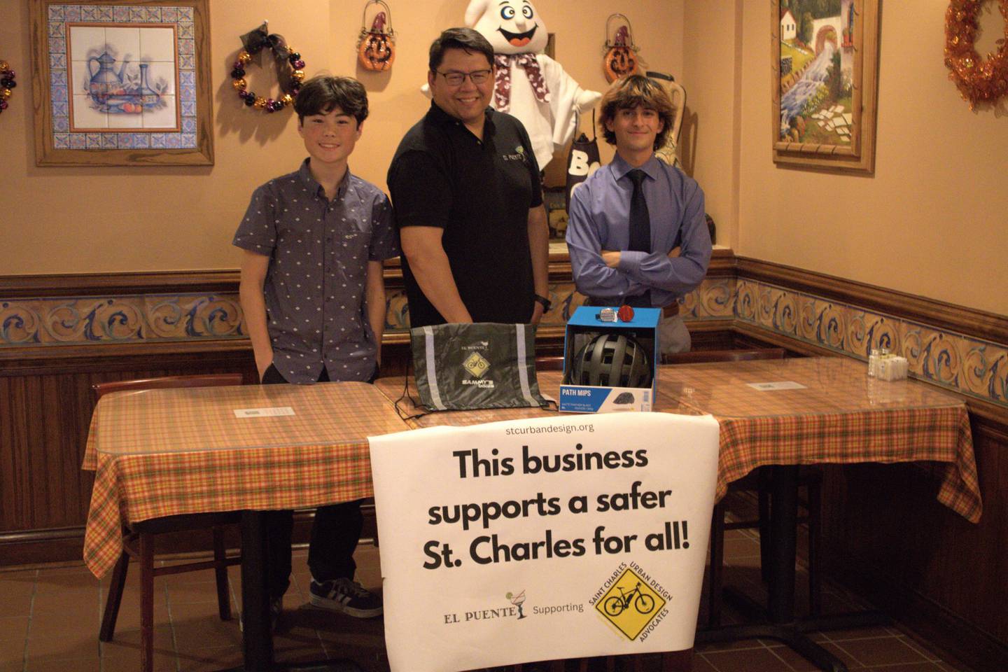St. Charles Urban Design Advocates founders James Bryner (left) and Calvin Reed (right) with El Puente owner David Jimenez (center) presenting Bicycle Safety Kits that will be donated to local restaurant workers.