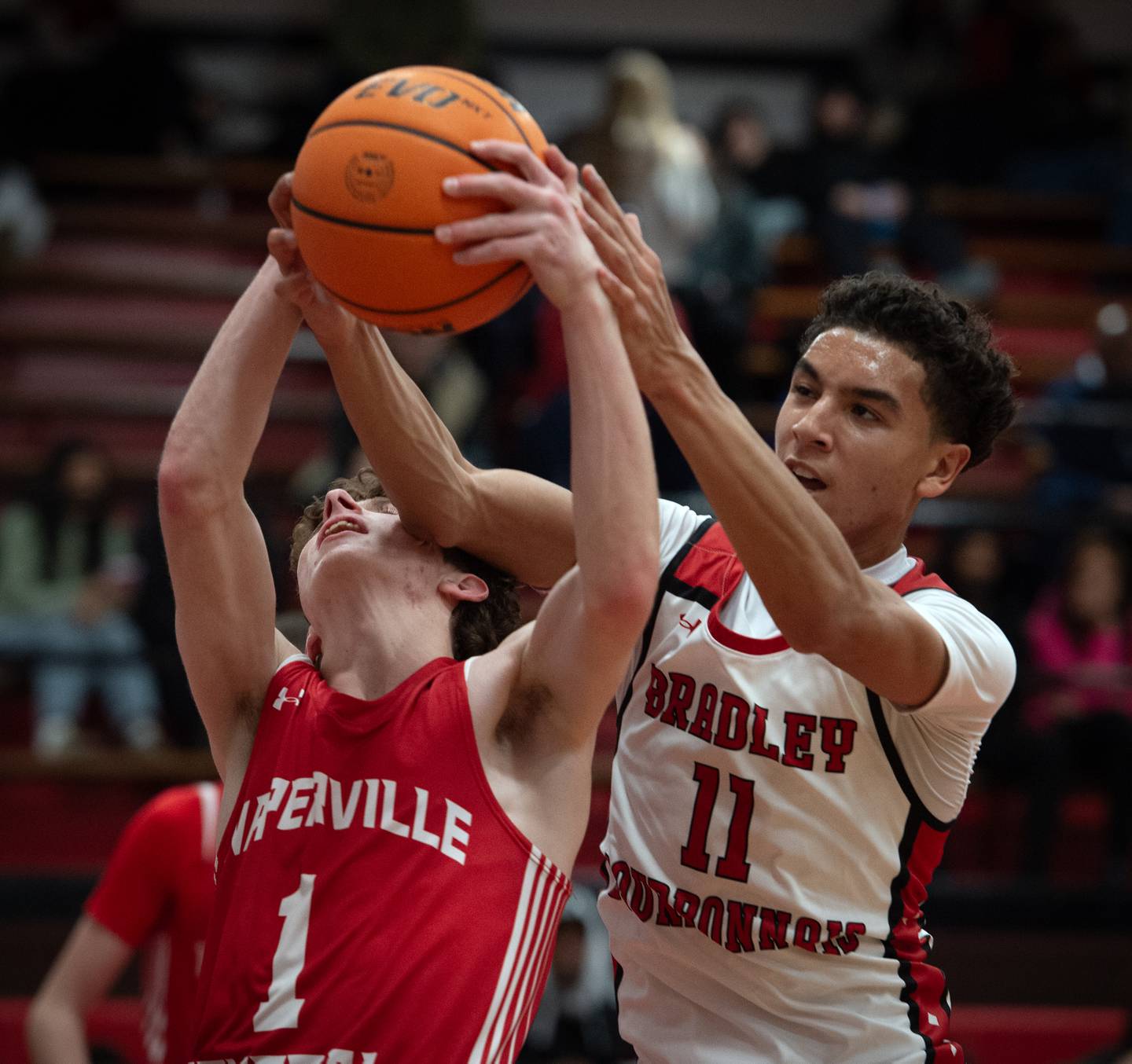 Bradley-Bourbonnais's Trey Lawrence, right, and Naperville Central's TJ Hillman, left, try to bring in a rebound in a game on Monday, December 15, 2025.