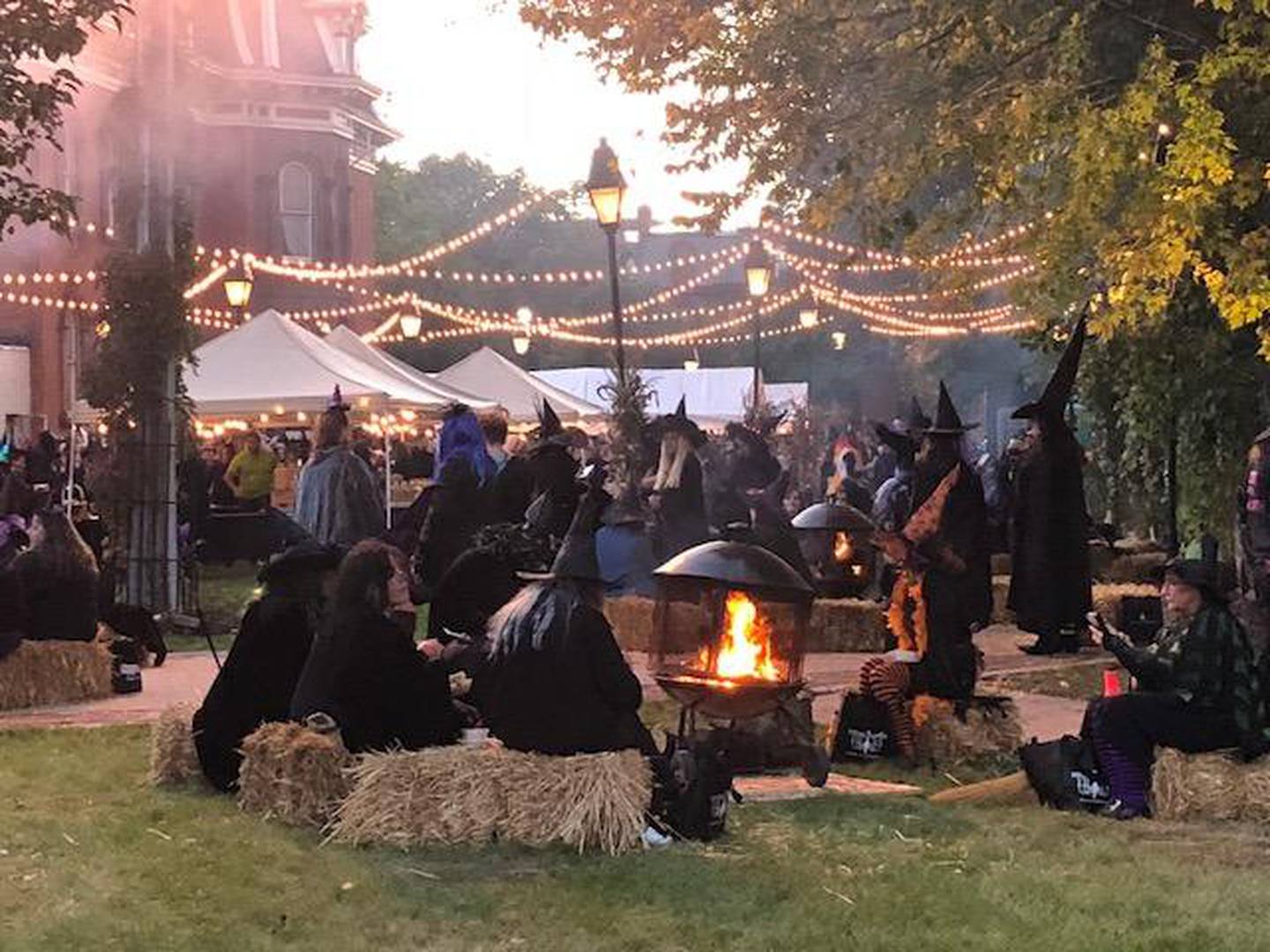 Women, dressed as witches, sit around a fire in the courtyard during Witches Night Out Thursday night in Joliet.