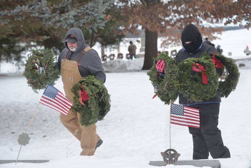 Volunteers Anne Stevens of Oregon (right) and Craig Beauchem braved bitter cold temperatures to lay wreaths on veteran graves at the Daysville Cemetery during the Wreaths Across America program on Saturday, Dec. 13, 2025.
