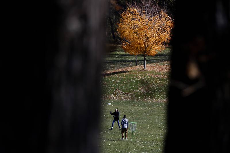 People throw a flying disc Wednesday. Oct. 26, 2022, as they take advantage of wonderful fall day in Veteran Acres Park in Crystal Lake.