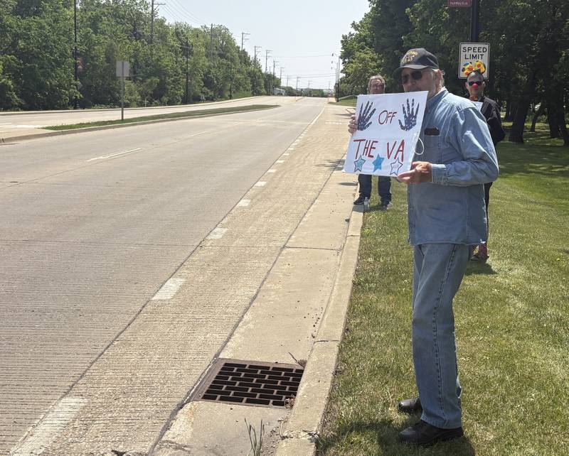 People hold up signs along Route 47 during a rally against President Donald Trump May 31, 2025.