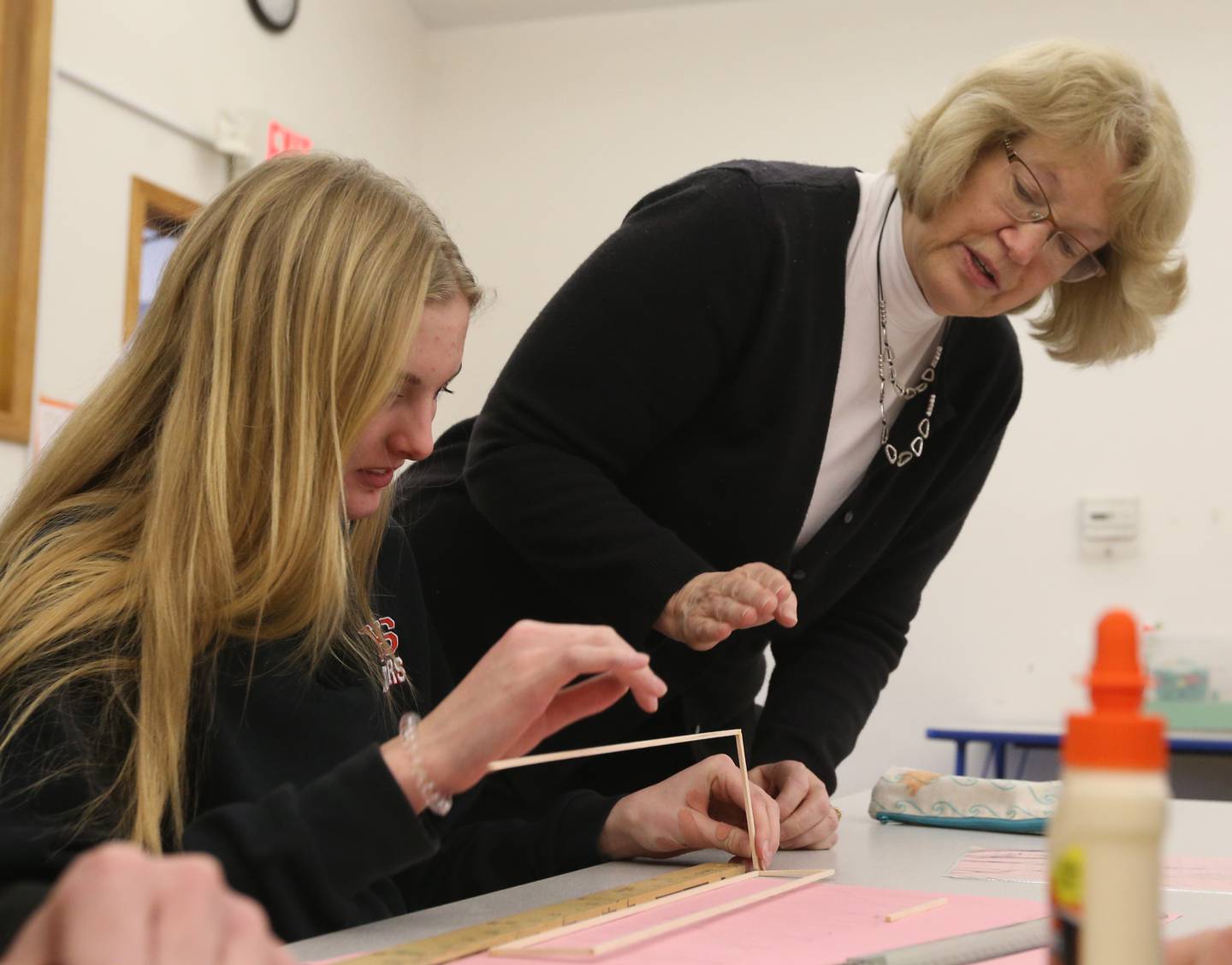 Mrs. Lynn Quick helps student Maggie Boudreau with building a bridge out of wood on Wednesday, March 22, 2023, at Holy Family School in Oglesby.