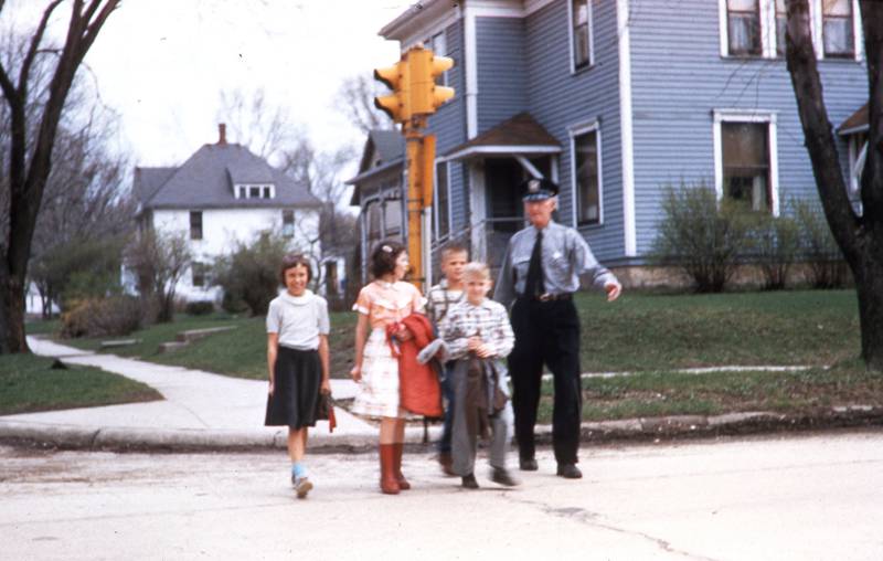 Crossing Guard Ed Donnelly guides students across Madison Street (Route 34) at Jackson Street in downtown Oswego in 1957. (Photo provided by the Little White School Museum)