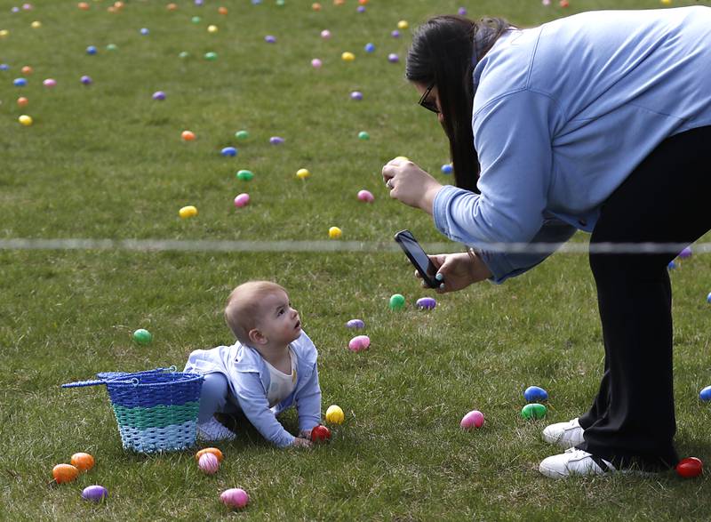 Alex Cinnamon, of McHenry, photographers her son, Miles, 7 months, on Saturday, April 19, 2025, during the Johnsburg Easter Egg Hunt at Sunnyside Memorial Park, in Johnsburg. Children hunted for 6,000 candy-filled eggs in three hunts divided by age group.