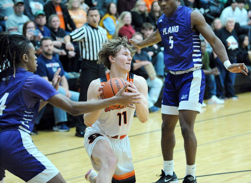 Sandwich's Nick Michalek (11) tries to keep control of the ball, while Plano defenders Tairon McGowan (left) and Waleed Johnson (5) press, during a varsity basketball game at Sandwich High School on Tuesday, Feb. 13, 2024.