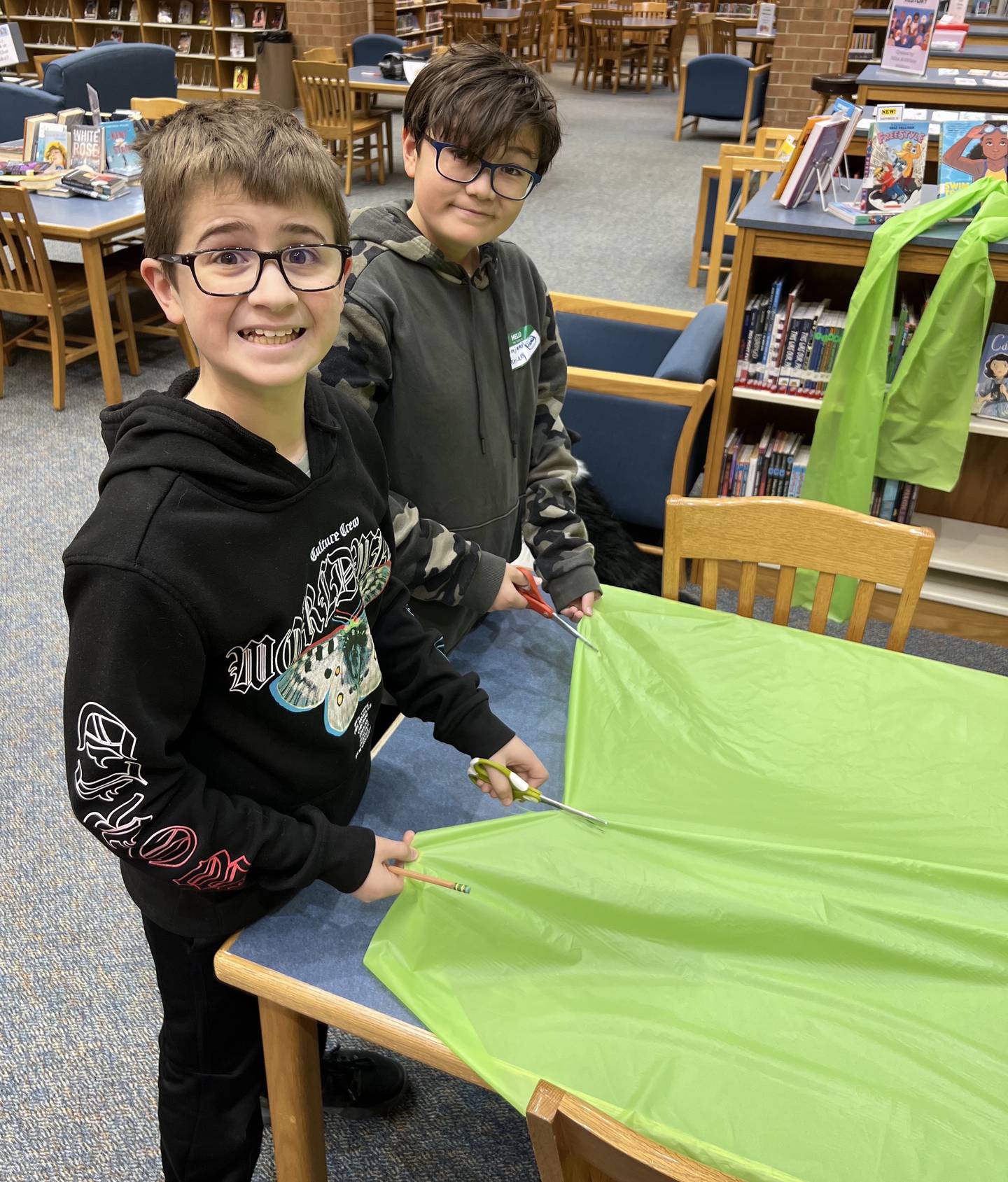 Andrew Kournetas (left) and Ben Krieg cut bright green plastic sheeting into strips so they can be tied as ribbons in Geneva to promote May as Mental Health Awareness Month.