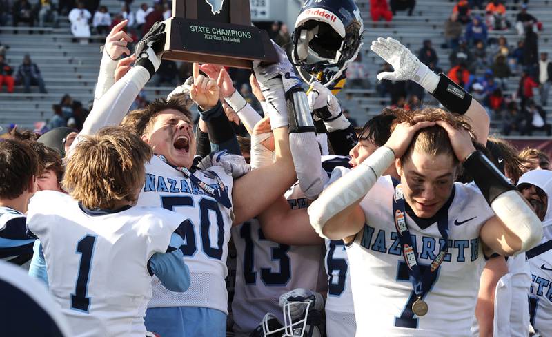 Nazareth's William Beargie and his teammates hoist the trophy after their IHSA Class 5A state championship win over Peoria Saturday, Nov. 26, 2022, in Memorial Stadium at the University of Illinois in Champaign.