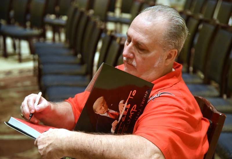 Huntley resident Gary DeRenzo writes a few notes in his copy of Donald Trump's book Letter to Trump during a McHenry County GOP committee fundraiser event Friday in Addison.