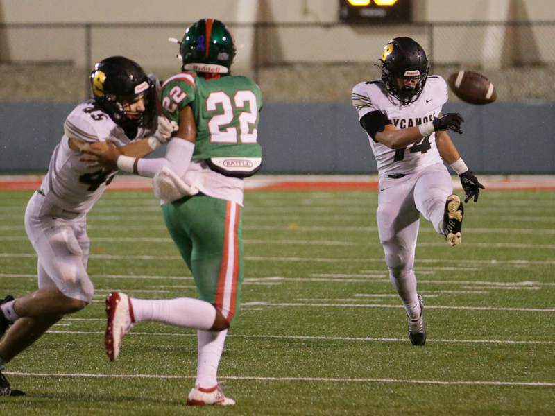 Sycamore's Kiefer Tarnoki (14) punts the ball as teammate Kaden Ladas (45) blocks L-P's Maaliak Madrigal (22) from blocking it on Friday, Oct. 14, 2022 at Howard Fellows Stadium in Peru.