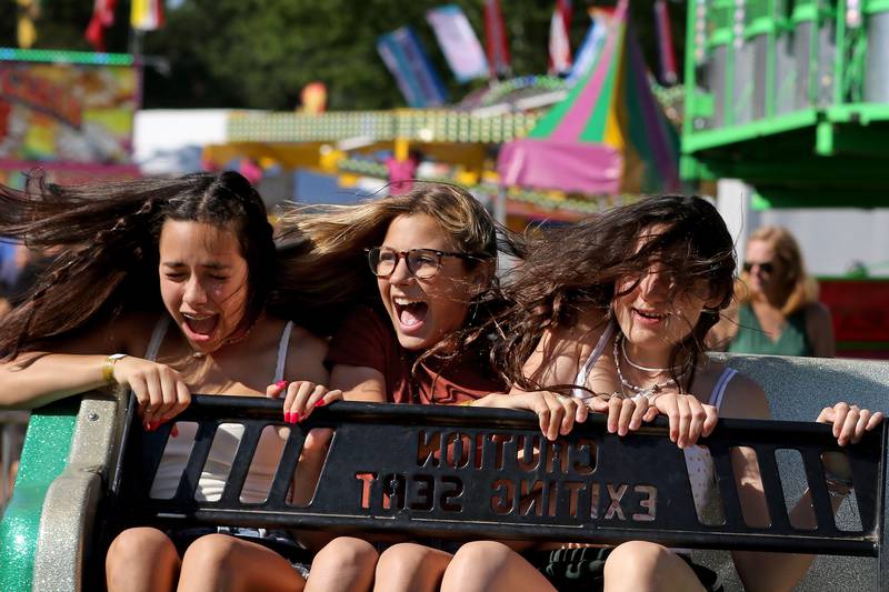 Friends (from left:) Vanessa Castro, Makayla Simonic and Lilly Claussen, all 13 and of Crystal Lake, feel the effects of centrifugal force on the Sizzler ride during the annual Lakeside Festival at the Dole and Lakeside Arts Park on Thursday, July 1, 2021, in Crystal Lake.