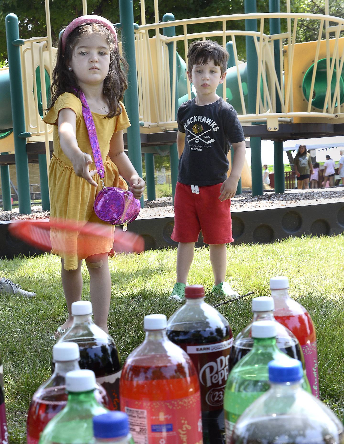 Norah and Crosby Tomato play a ring toss game Wednesday, July 5, 2023, at Grand Ridge Park for A Day On The Farm, an Ottawa Recreation program.