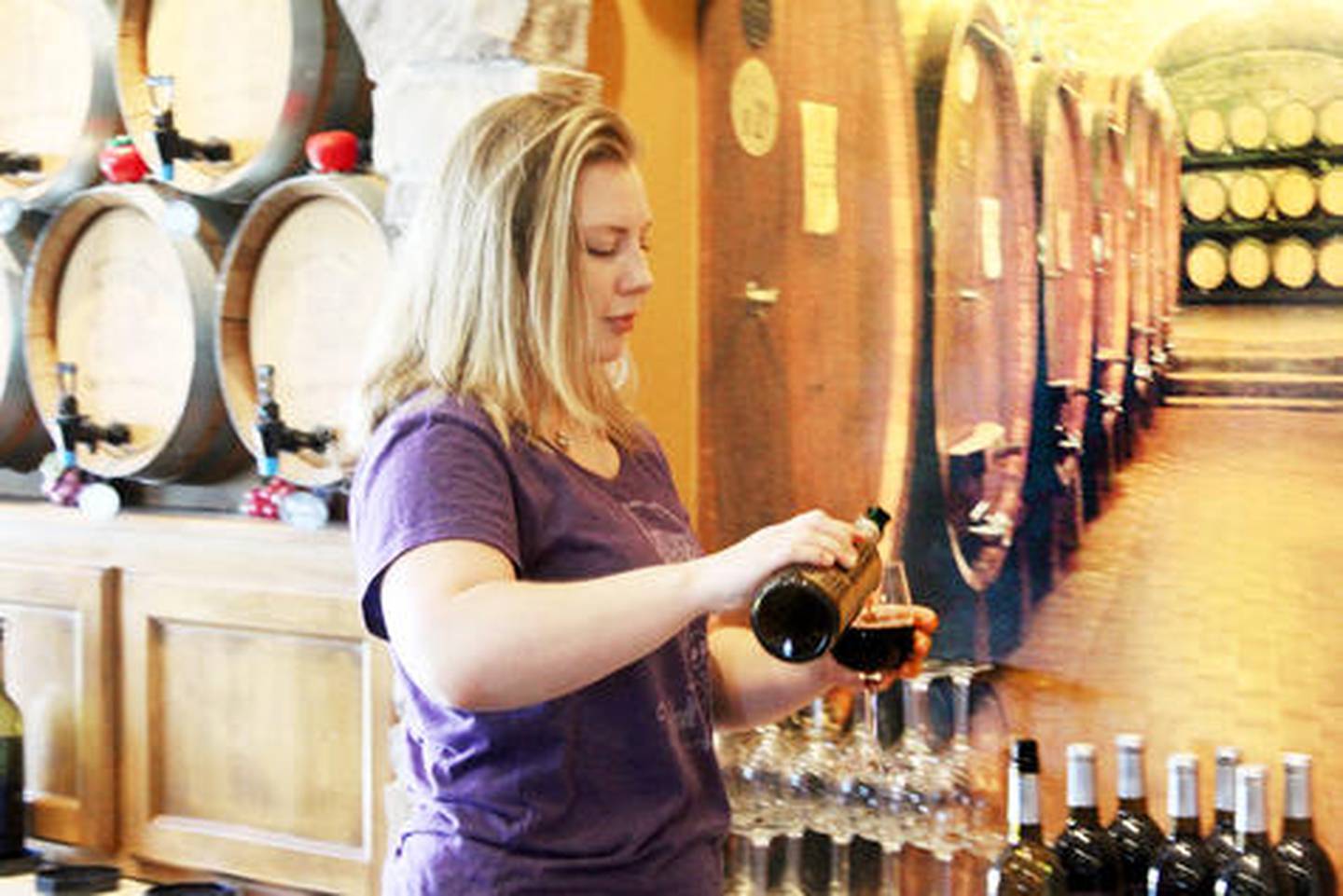 Jaime Schmidt of Fergedaboudit Vineyard and Winery pours a drink for a customer from the tasting room.