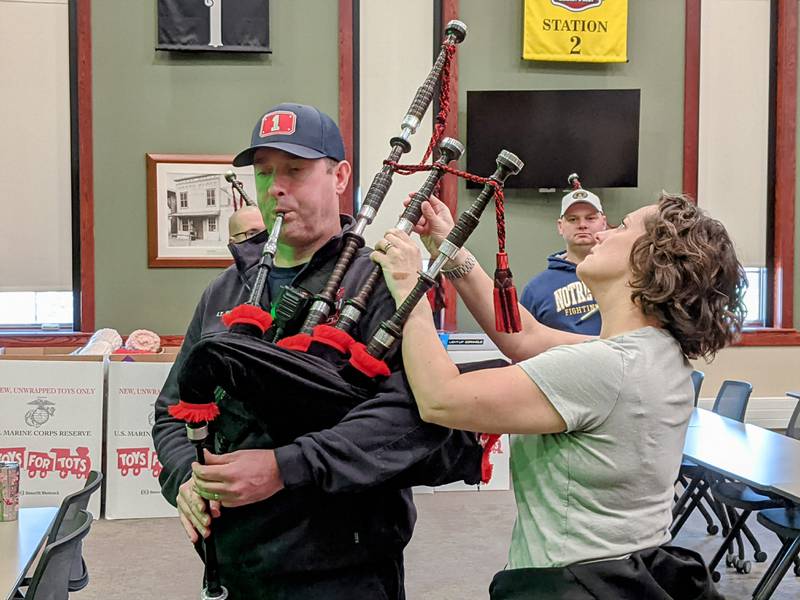 Music instructor Kate Longid helps Oswego Fire Protection District Lt. Eric Roberts, manager of the Oswego Firefighters Pipes and Drums Local 4773, during a recent rehearsal.