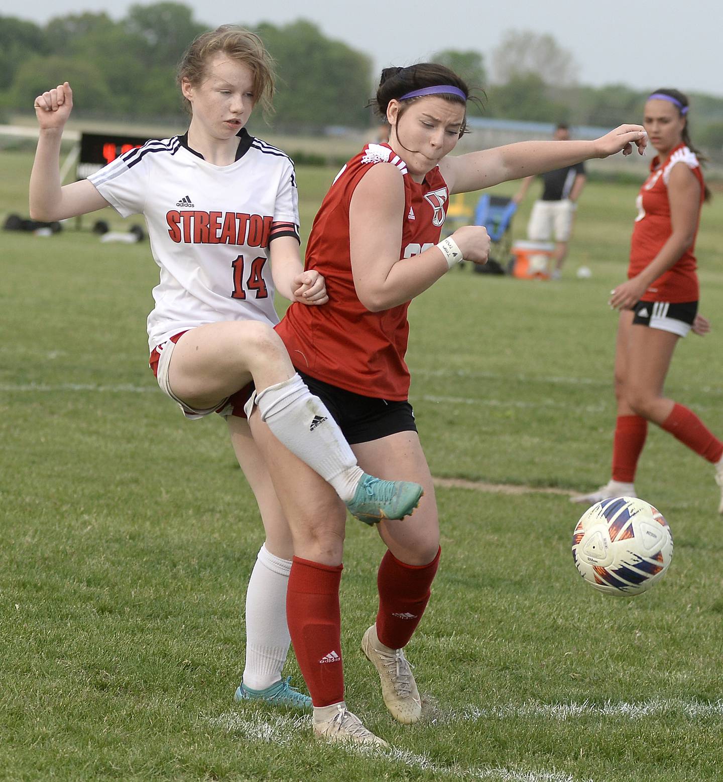 Bridget McGurk (14) kicks the ball through contact from Metamora's Maddie Morris Streator's Anna Russow (at left) works against Metamora's Lucy Mischler on Friday, May 19, 2023, during the championship match of the Class 2A Streator Regional at the Streator Family YMCA.
