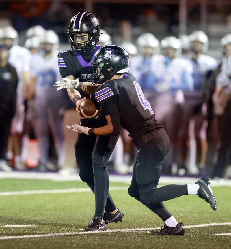 Downers Grove North's Owen Lansu  (1) hands off the ball to Caden Chiarelli (4) for a long touchdown run during the IHSA Class 7A playoff football game Friday, Oct. 31, 2025 in Downers Grove.