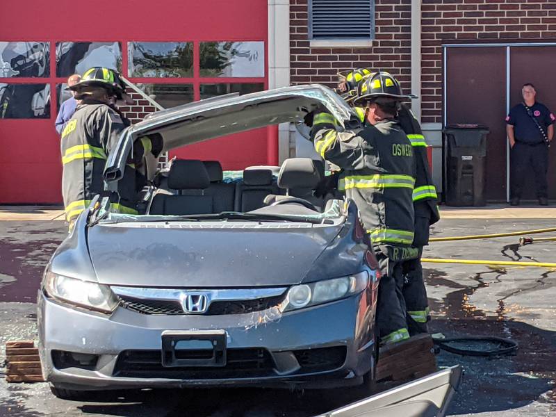 Firefighters with the Oswego Fire Protection District remove the hood from a car as part of a vehicle extrication demonstration during a joint safety campus open house between the Oswego Fire Protection District and the Oswego Police Department on Oct. 11, 2025.