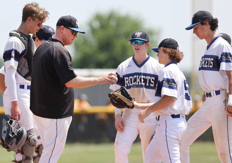 Burlington Central head coach Kyle Nelson hands the ball off to Matt Kowalik to pitch in relief during their Class 3A sectional final game against Sycamore Saturday, June 3, 2023, at Kaneland High School in Maple Park.