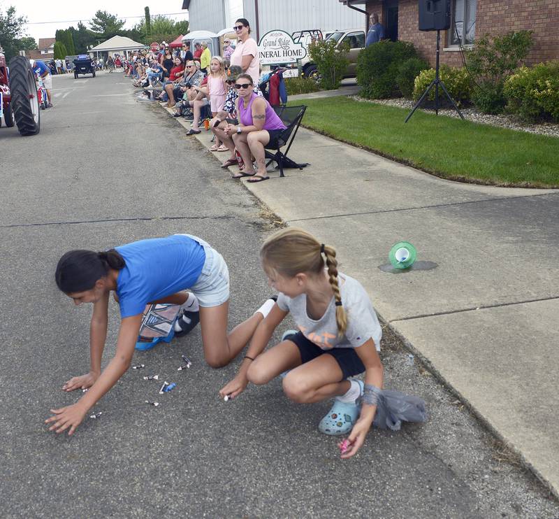 Children along the parade route work to gather candy treats tossed their way during the Community Fest Parade Sunday in Grand Ridge.