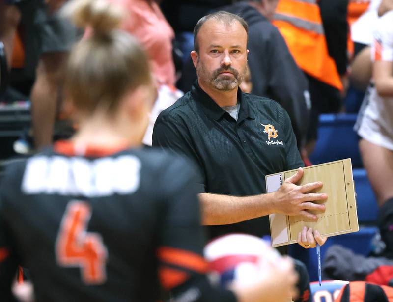 New DeKalb and former Genoa-Kingston head volleyball coach Keith Foster signals DeKalb's Maddi Hollar before her serve Wednesday, Sept. 11, 2024, during their game at Genoa-Kingston High School.