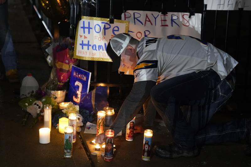 Brandon Metzger lights candles before a prayer vigil for Buffalo Bills defensive back Damar Hamlin outside of the University of Cincinnati Medical Center, Tuesday, Jan. 3, 2023, in Cincinnati. Hamlin was taken to the hospital after collapsing on the field during an NFL game against the Cincinnati Bengals on Monday night.