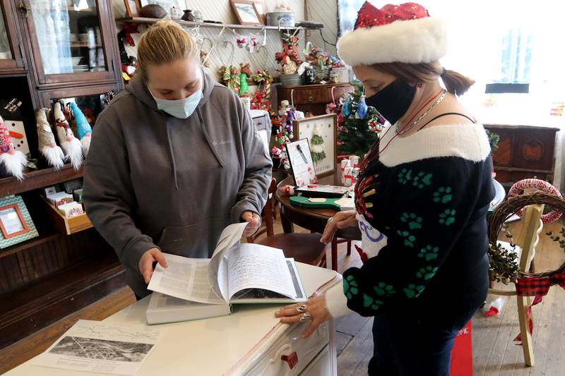 General Store employees Chloe Scott, left, and Sharon Consentino look over a book on the history of Greenwood Township on Tuesday, Dec. 15, 2020, inside their store in Greenwood. The building has been a general store since its construction in 1894 and was also the township's post office.