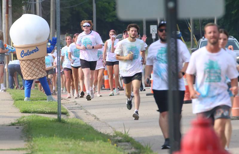 Runners sprint past "Scoopie" the Culvers mascot during the Arukah Institute of Healing Freedom Color Run on Friday, July 4, 2025 at Soldiers and Sailors Park in Princeton.