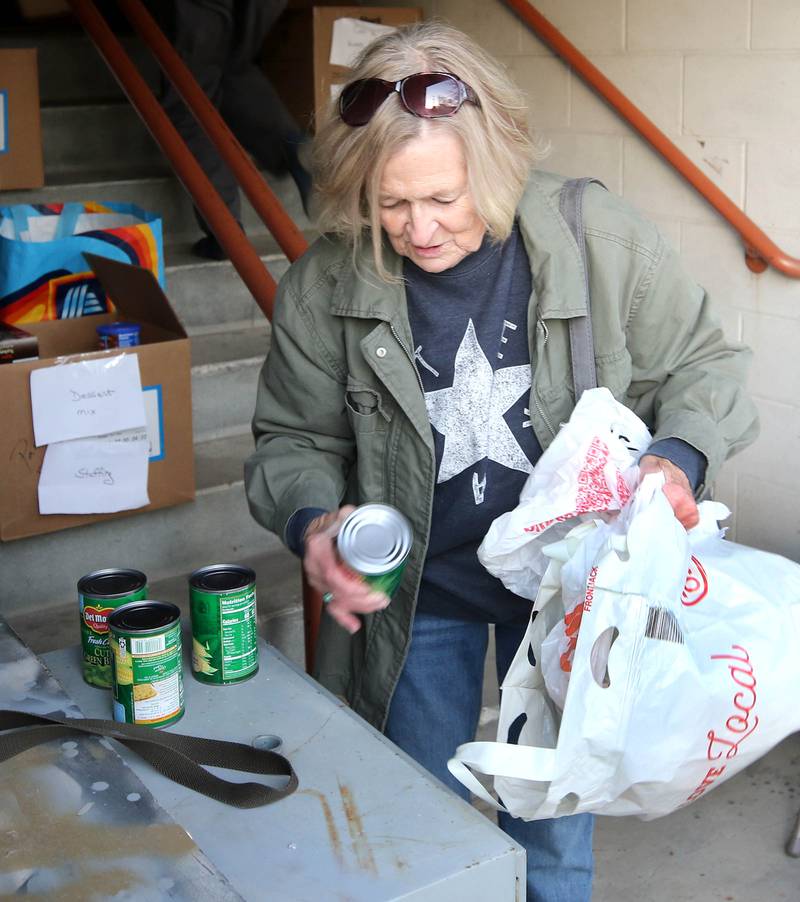 Kathy Cain, from Sycamore, takes items out of her bag for donation to the food drive Tuesday, Nov. 12, 2024, at the Stage Coach Theatre in Dekalb. The food collected will be assembled into dinner boxes to provide local families with a Thanksgiving meal.