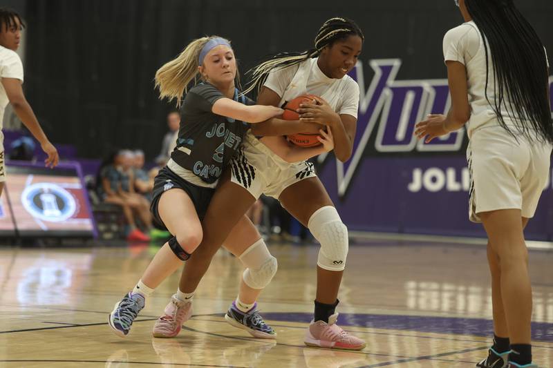 Joliet Catholic’s Ingrid Troha tries to rip the ball away from Joliet West’s Makayla Chism in the WJOL Basketball Tournament at Joliet Junior College Event Center on Monday