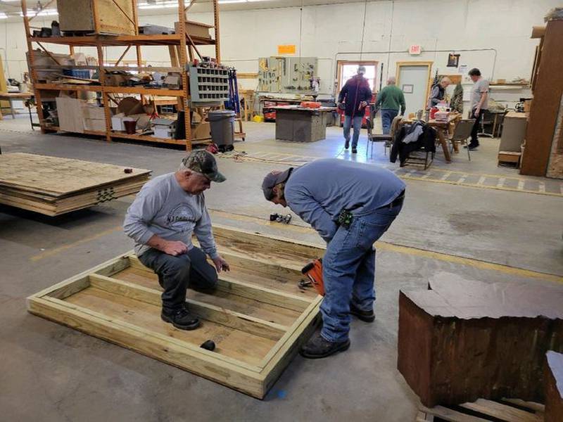 Volunteers work on construction parts of the shed that will be used to house sleds for public use at Byron Forest Preserve.