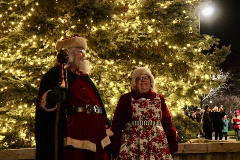 Backlit by the Christmas tree at Library Plaza in downtown Sterling, Santa and Mrs. Claus take in the pageantry of the Seasonal Sights and Sounds festival on Friday