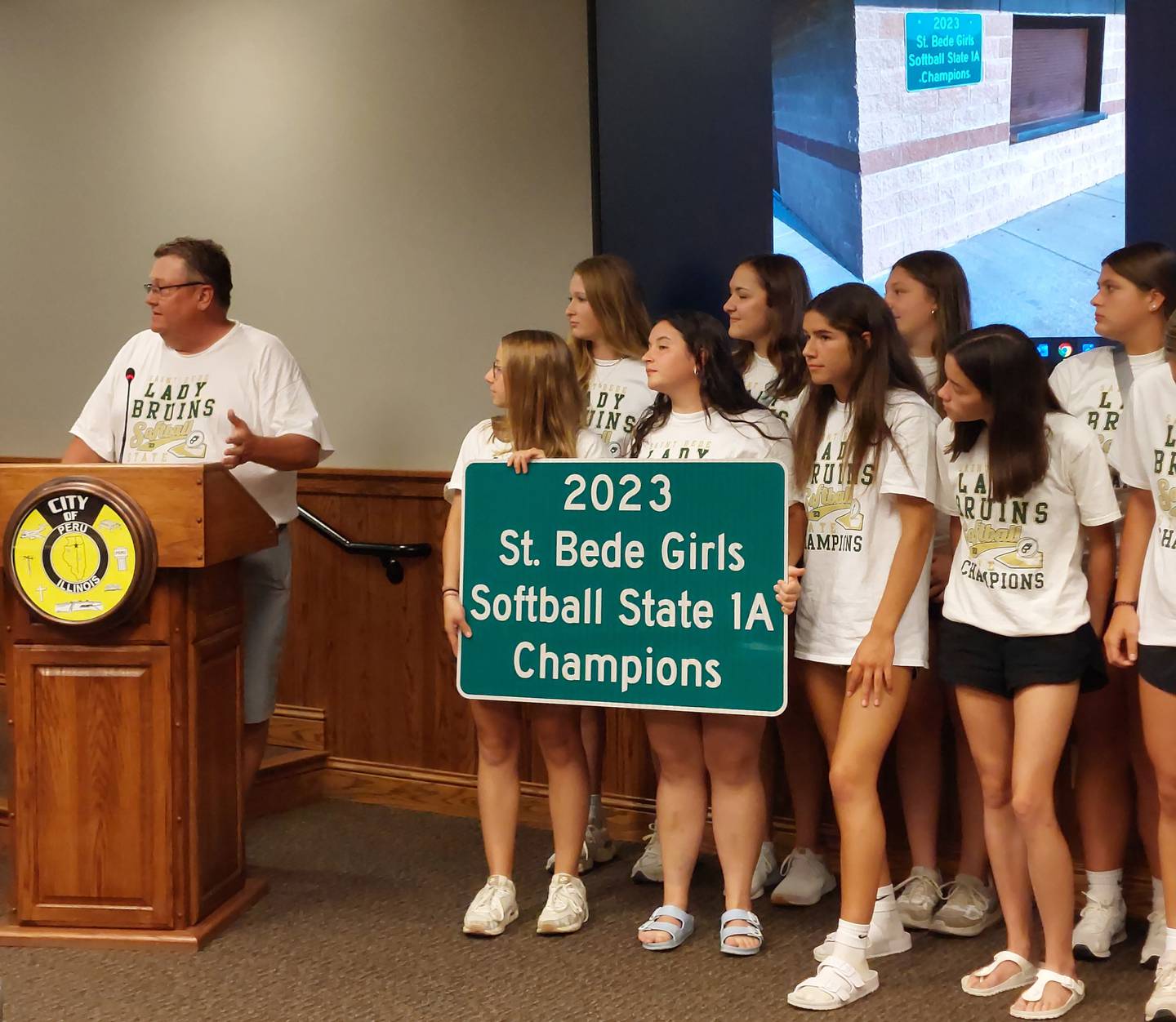 St. Bede softball coach Shawn Sons talks about the team's champions run Wednesday, July 5, 2023, as it was honored by the Peru City Council with a sign.