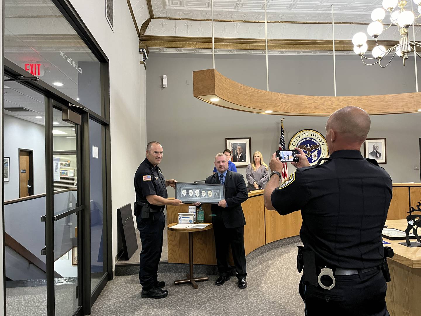 Dixon Police Department’s Deputy Chief Matt Richards (right) takes a picture of Deputy Chief Doug Lehman (left) and former Sgt. Matthew Coppotelli during a city council meeting Monday, Aug. 5. Coppotelli retired on Jan. 18, 2024 after 27 years with the department and now serves as Polo's chief of police.