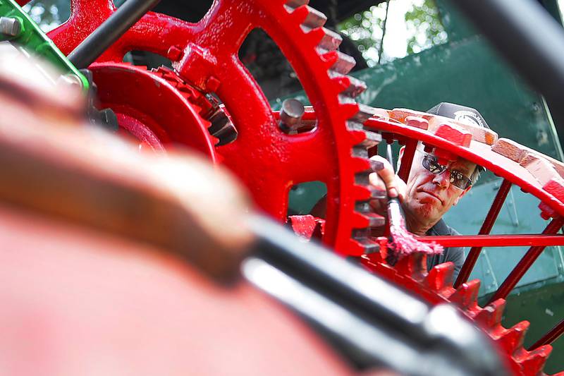 Show director Dan Stevens puts grease on the gears for the 1916 steam engine made by the Illinois Thresher Company in Sycamore with a paintbrush before it makes its first appearance in the parade on Thursday, August 14, 2014, at the Northern Illinois Steam Power Club's Steam Show and Threshing Bee at Taylor Marshall Farm in Sycamore.