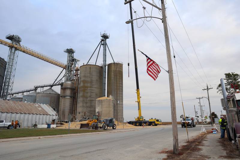 Harvested beans cover the ground as an Ameren worker tends to downed power lines after a concrete grain bin collapsed on Wednesday, Oct. 15, 2025, at the Donovan Farmers Co-Op Elevator in downtown Martinton.