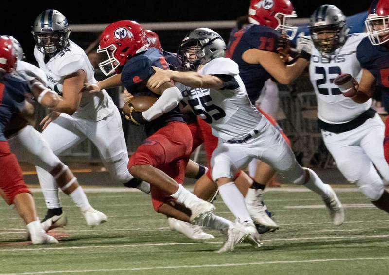Oswego East's Dylan Crawford (55) hits West Aurora's Jeremiah Johnson (6) in the backfield for a loss during a high school football game at West Aurora High School in Aurora on Friday, Sep 24, 2021.