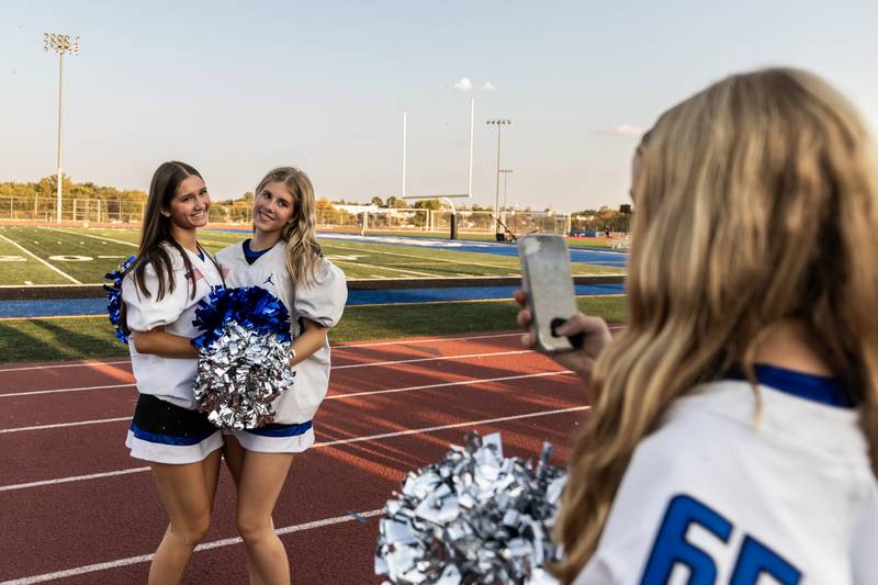 Varsity poms members Charlotte Hainzinger and Julia Chase get their photo taken by Taylor Bailey before varsity football game against Metea Valley at Lincoln-Way East on Oct. 3, 2025.