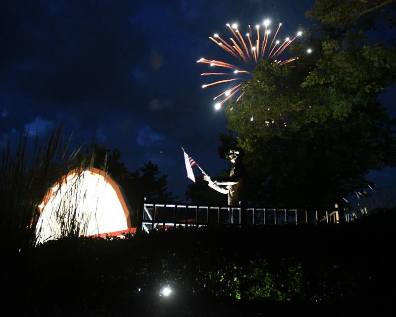 A statue of W. "Dee" Palmer, the former director of DeKalb Municipal Band, stands outside of the Band Shell as the DeKalb Municipal Band performs its Independence Day concert while fireworks explode during the show Monday July 4, 2022 in DeKalb.