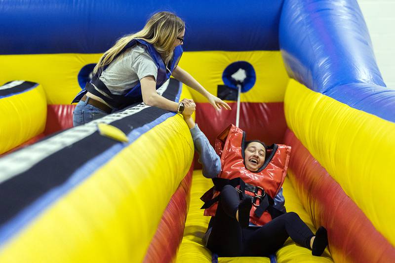 Haliegh Bennett, left, lends a hand to Allie Royer on Wednesday, Feb. 1, 2023 after the two played around on a slingshot inflatable during Sauk Valley College’s SaukFest. The event was put on to welcome students back to SVCC for the spring semester.