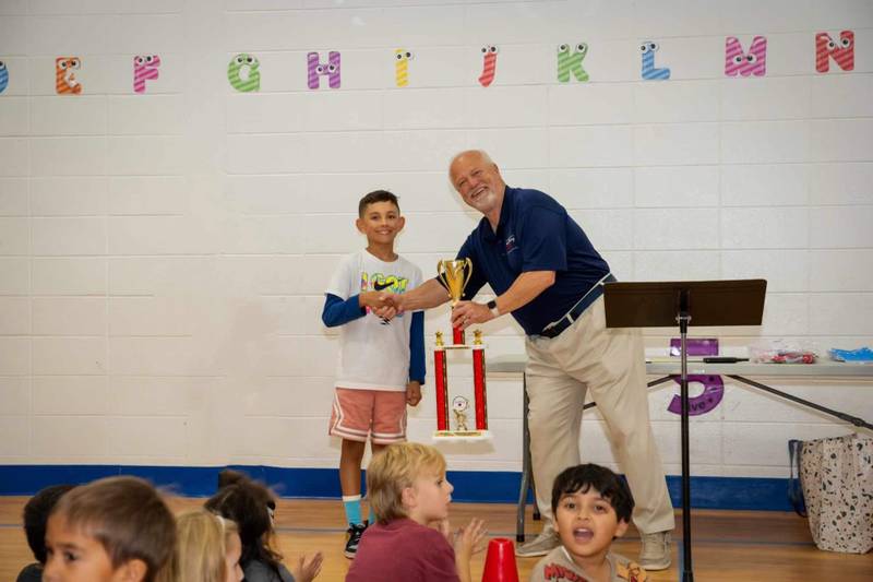 Fifth grader Leo Bonilla accepts Neubert Elementary School's Hunger Champion award from food bank board member and volunteer facilities manager Chuck Bumbales for collecting over 10,000 pounds of food for the D300 Food Pantry.