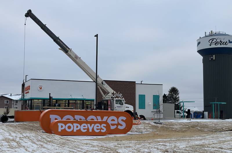 Crews begin to raise Popeyes signs in place for the new location near the intersection of May Road and Trompeter Road on Tuesday, Dec. 3, 2024 in Peru.