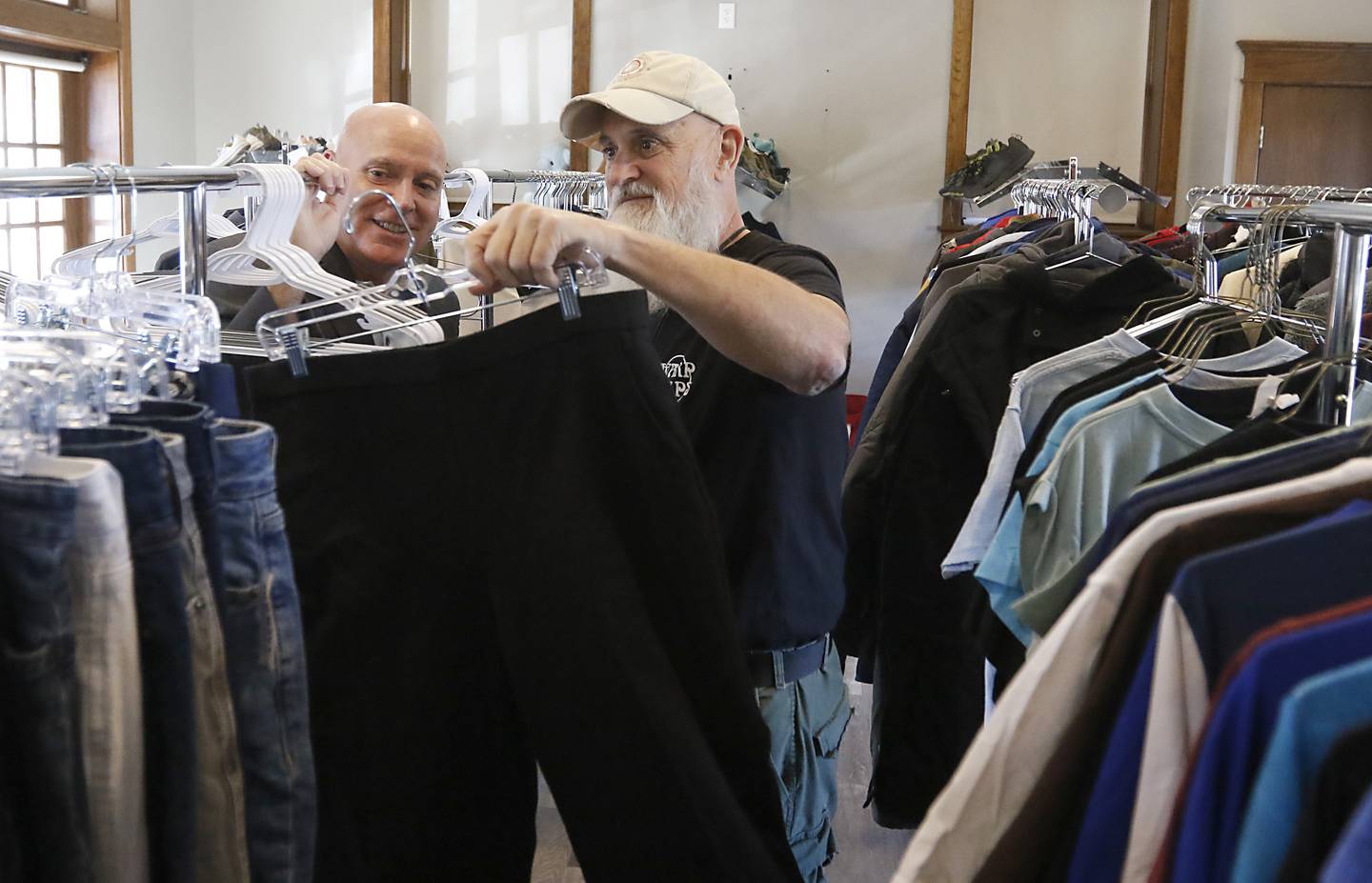 Rob Mutert of Warp Corps and Tom Wilson of MBI and MBI Cares looks at a pair pants the will be in the new shop for homeless and low income people in the Woodstock Depot on Wednesday, Oct. 23, 2024, as they add stock to the shop in Woodstock.