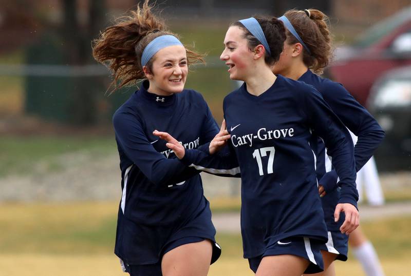Cary-Grove’s Ellie Santucci, right, is greeted by Sam Skerl, left, after a first-half goal against Woodstock North during girls varsity soccer at Cary Thursday night.
