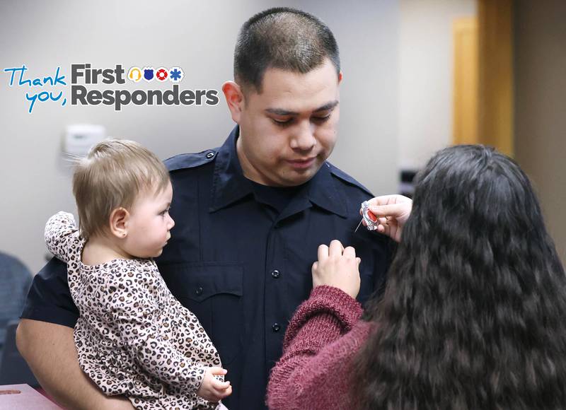 New Sycamore firefighter Carlos Aburto has his badge pinned on by girlfriend Stephanie Starks as he holds daughter Sophia Aburto following being officially sworn in Monday, April 1, 2024, during the Sycamore City Council meeting in the chambers at Sycamore Center.